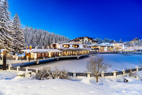 a resort in the snow with a pond at Aurelius Imparatul Romanilor Hotel & SPA in Poiana Brasov