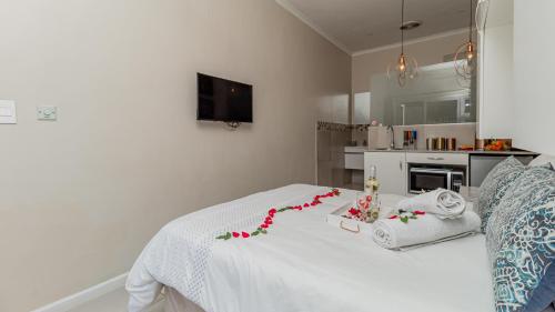 a bedroom with a white bed with flowers on it at Sea Breeze Guest House in Bloubergstrand