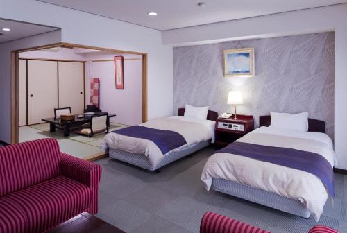 a hotel room with two beds and a couch at Hotel Sunmi Club in Atami