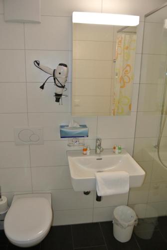 a white bathroom with a toilet and a sink at Hotel Garni Bären Bazenheid in Bazenheid