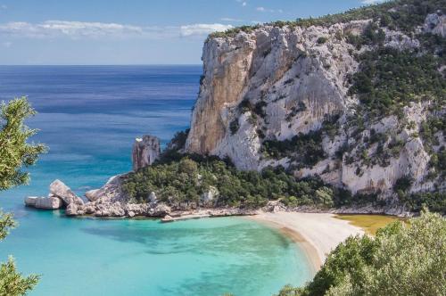 a view of a beach with a large cliff at Residence Cala Viola in Cala Liberotto