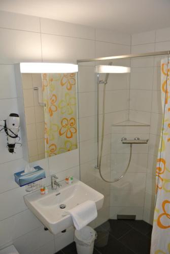 a white bathroom with a sink and a shower at Hotel Garni Bären Bazenheid in Bazenheid