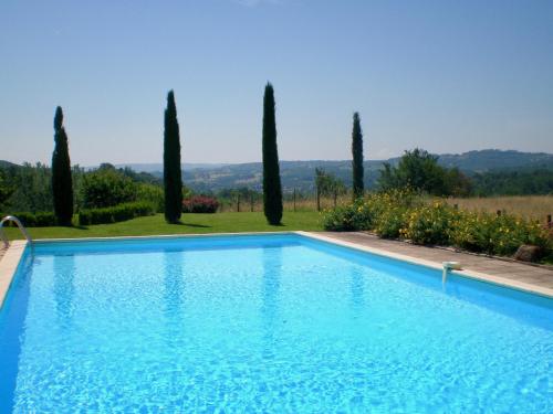 une piscine avec des arbres en arrière-plan dans l'établissement Domaine Leyvinie, gite Mourvedre, close to the Dordogne, à Perpezac-le-Blanc
