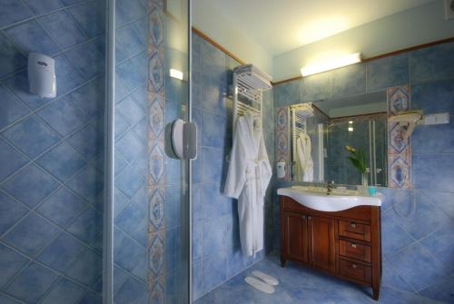 a blue tiled bathroom with a sink and a shower at Hotel Basztowy in Sandomierz