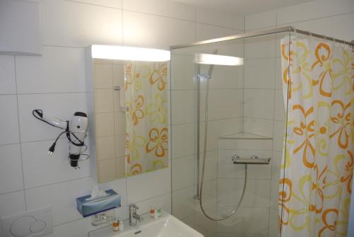 a bathroom with a shower and a sink and a mirror at Hotel Garni Bären Bazenheid in Bazenheid