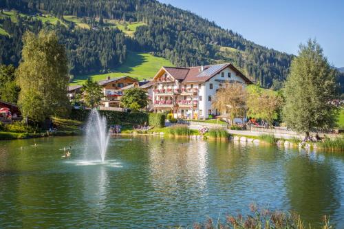 a fountain in a lake in front of a building at Aparthotel am Reitecksee in Flachau
