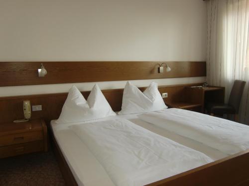 a bed with white sheets and pillows on it at Pension Lahn in Rablà