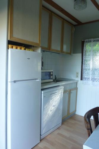 La cuisine est équipée d'un réfrigérateur blanc et d'un lave-vaisselle. dans l'établissement 3 Gites - Relais Du Saussay Pertheville Ners, à Pertheville-Ners