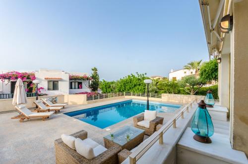 een zwembad met ligstoelen en een huis bij Anna Maria Village in Chersonissos