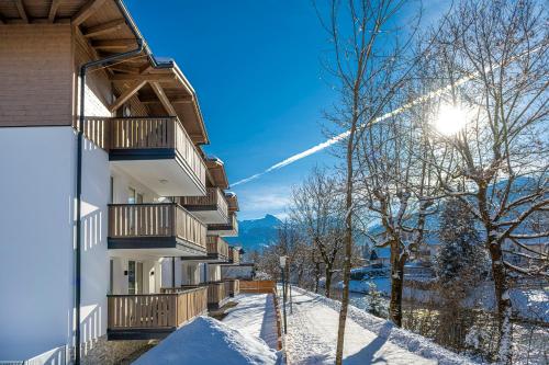 巴特霍夫加施泰因的住宿－Haus Bergblick by AlpenTravel，雪中,天空中阳光下的建筑
