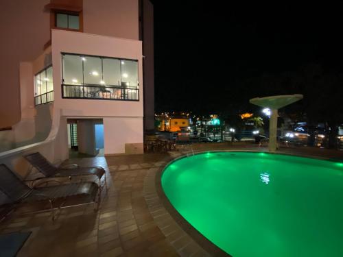 a swimming pool at night in front of a building at HD Plaza Hotel in Assis