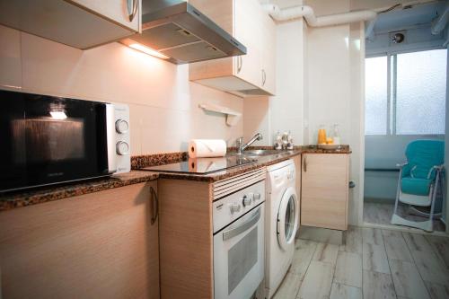 una pequeña cocina con microondas y lavavajillas en Sirenas Playa Ha Apartment en Cádiz