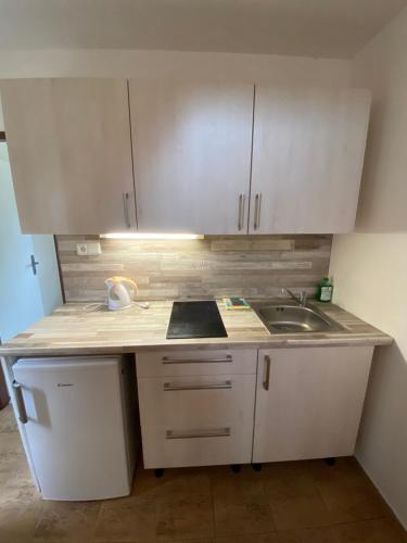 a small kitchen with white cabinets and a sink at Chaty a Apartmány Hracholusky Kemp Kosatka in Pňovany