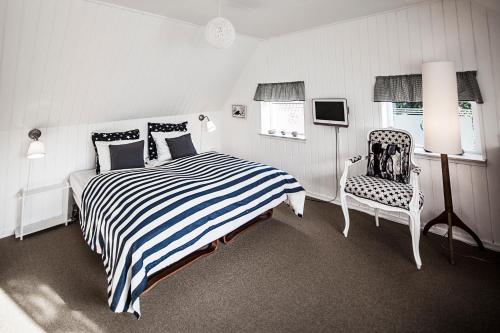 a bedroom with a black and white striped bed and a chair at Norsminde Kro Anneks in Odder