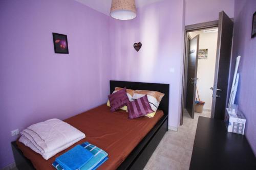 een kleine kamer met een bed met paarse muren bij Cozy apartment in Greece in Flogita