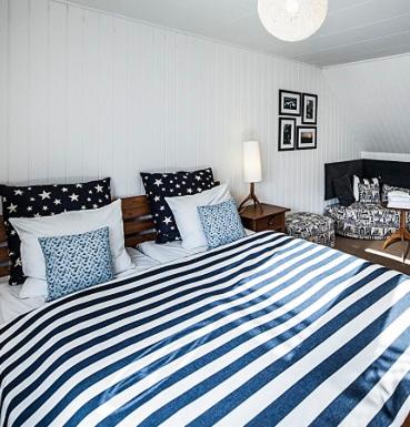 a bedroom with a blue and white striped bed at Norsminde Kro Anneks in Odder