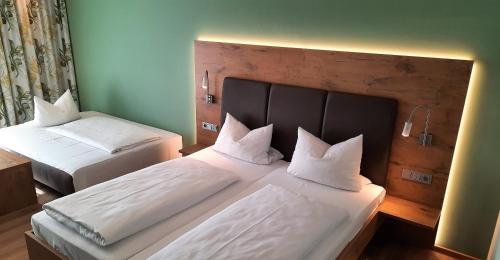 a bedroom with two beds with white sheets and pillows at Hotel Bergwirt in Herrieden