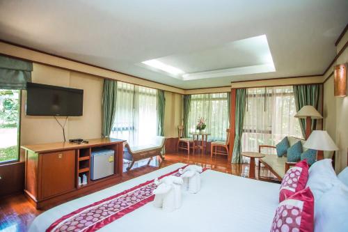 KaengsophaにあるSappraiwan Elephant Resort & Sanctuaryのベッド1台、薄型テレビが備わるホテルルームです。