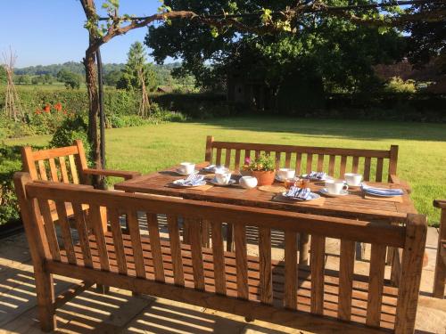 una mesa de madera con platos y tazas. en Hurst Farm B&B, en Crockham Hill