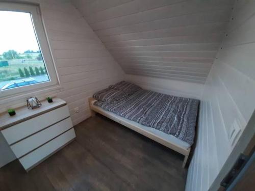 niewielka sypialnia z łóżkiem i oknem w obiekcie Domki Złote Piaski w Darłówku