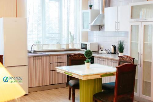 een keuken met een tafel en stoelen en een koelkast bij Апартаменти на Новоолександрівській in Charkov
