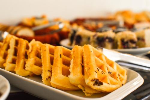 a plate of waffles on a table with other plates of food at Pousada Tango in Gramado