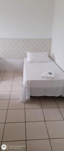 a bedroom with a white bed and a tiled floor at Hotel Norte Blu in Blumenau
