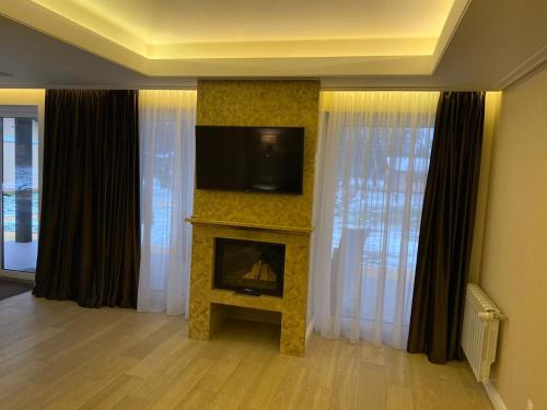 a living room with a fireplace and a flat screen tv at Park-Hotel Tihiy Les in Prokhorovka