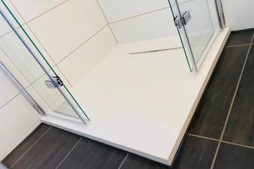 a shower with glass doors and a wooden floor at Moderner Einraumbungalow auf eigenem Grundstück in Flecken Zechlin