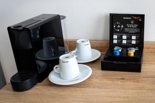 a coffee maker with two cups and a box on a table at LivInn by Trotmannia in Dortmund