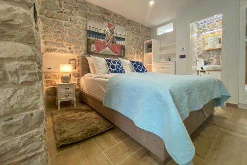 a bedroom with a large bed and a stone wall at La Corte di Kate-2 in Biograd na Moru