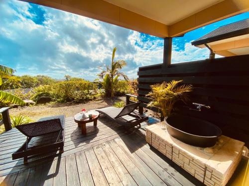 a wooden deck with a bath tub and a table at Yakushima Cottage Morino Fairy in Yakushima