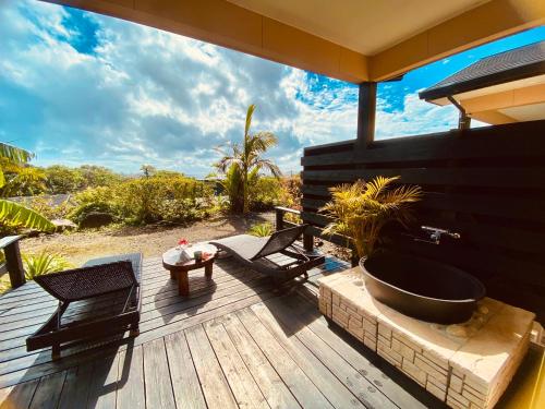 a wooden deck with a bath tub and a table at 森のフェアリー Cottage Morino Fairy All cotage with open-air bath with sea view or river view in Yakushima