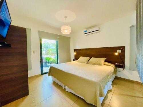 a bedroom with a large bed and a flat screen tv at BOULEVARD departamentos in Mina Clavero