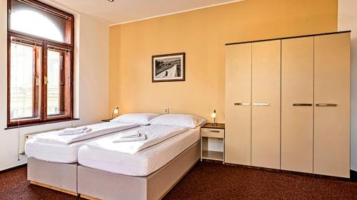 a bedroom with a large white bed and a cabinet at Penzion Dvořákova in Brno