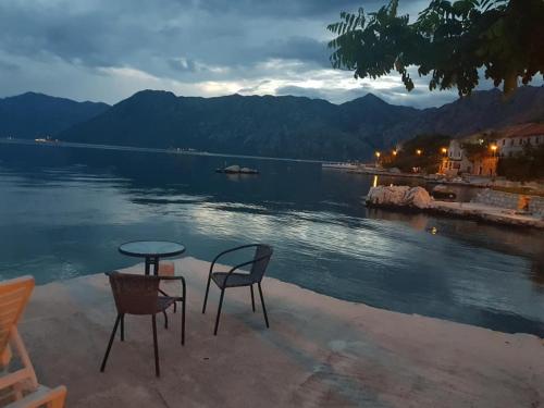 a table and chairs sitting next to a body of water at Apartments Ponta in Kotor