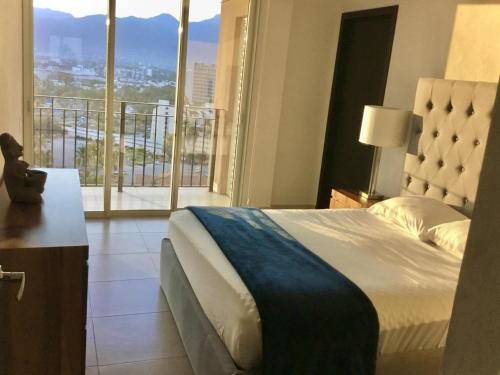 Cette chambre comprend un lit et une grande fenêtre. dans l'établissement Apartamentos Grand Venetian Puerto Vallarta, à Puerto Vallarta