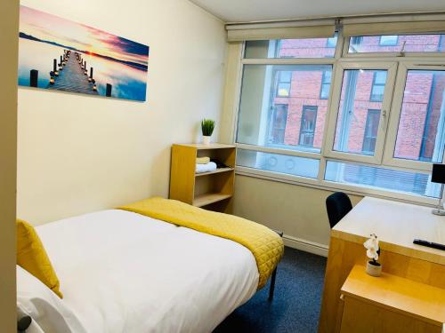 1 dormitorio con cama, escritorio y ventana en Sangha House, en Leicester