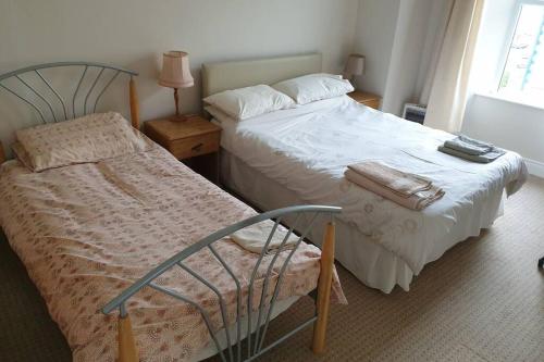 a bedroom with two beds and a chair and a window at 2 bed house at Ballycastle seafront in Ballycastle