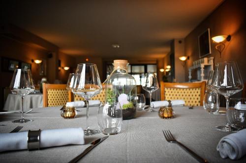 a table with wine glasses and a bottle on it at Le Cheval Blanc - Lac du Der - Logis Hotel in Giffaumont