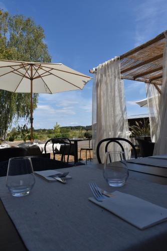 a table with two wine glasses and an umbrella at Le Cheval Blanc - Lac du Der - Logis Hotel in Giffaumont