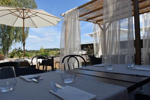 a table with wine glasses and an umbrella at Le Cheval Blanc - Lac du Der - Logis Hotel in Giffaumont