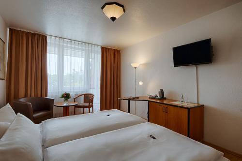 ベルナウ・バイ・ベルリンにあるコンフォート ホテル ベルナウのベッド2台とテレビが備わるホテルルームです。