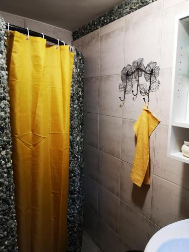 a shower with a yellow shower curtain in a bathroom at HIŽA BAKE ROZE in Gornja Konjšćina