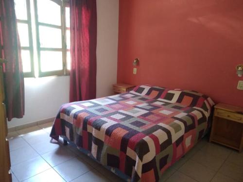 a bedroom with a bed with a colorful blanket on it at cabaña alojamiento Canto de las Aves in San Rafael