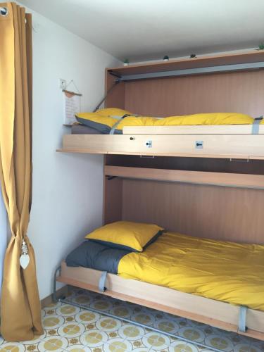 two bunk beds in a room with yellow pillows at Studio L’ARGENTIERE PLAGE in La Londe-les-Maures