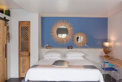 a bedroom with a bed with a blue wall and two mirrors at Graviana - Pedra Azul Charming House in Lagoa