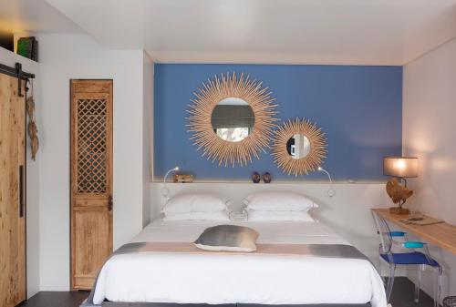 een slaapkamer met een bed met een blauwe muur en 2 spiegels bij Graviana - Pedra Azul Charming House in Lagoa