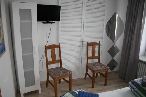 Zimmer mit 2 Stühlen, einem TV und einem Bett in der Unterkunft Frey - Ferienhaus über zwei Etagen mit Terrasse in Eggebek