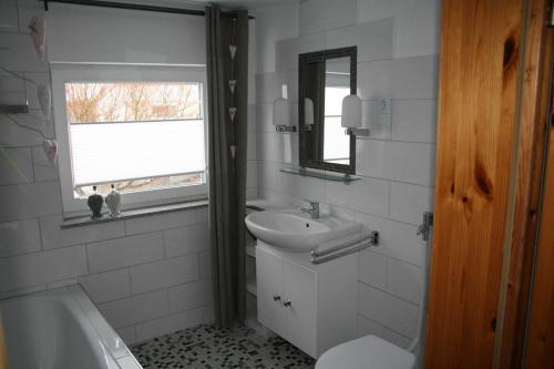 a bathroom with a sink and a toilet and a tub at Frey - Ferienhaus über zwei Etagen mit Terrasse in Eggebek